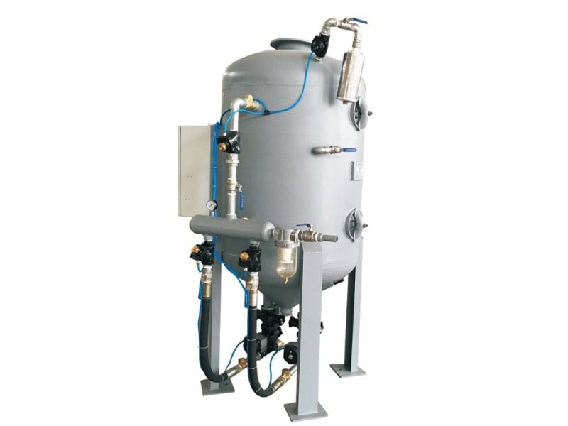 Industrial TS-900-2 filtration/storage unit with silver-gray cylindrical tank, four metal legs, top-mounted valves/piping, and side connections.