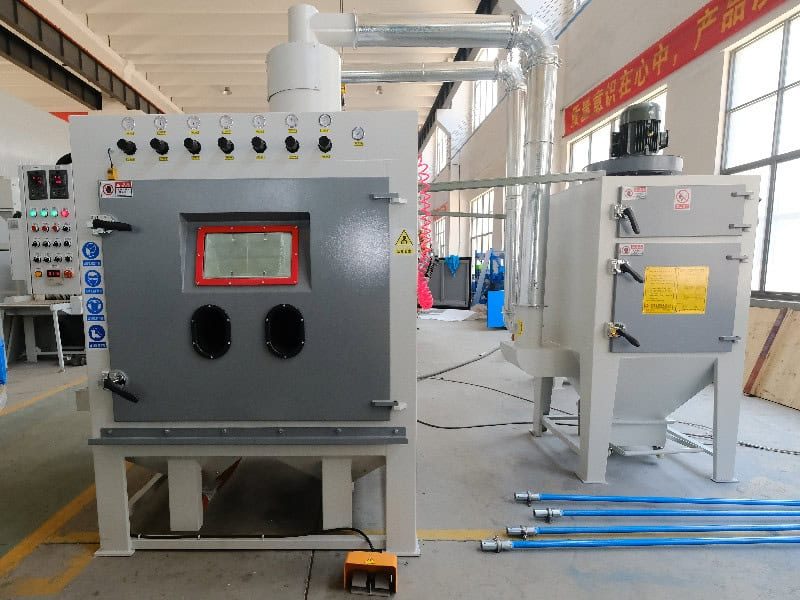 Industrial ​​Lining plate sandblasting machine​​ with control panel and black connectors, paired with gray-white auxiliary equipment in factory setting.
