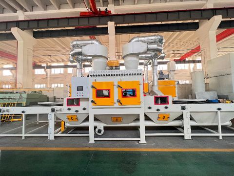 Orange-white conveyor sandblaster with dual dust collectors and automated belt system - high-volume surface preparation for industrial parts processing.