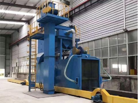 Large blue industrial beam shot blasting machine with yellow ladder and roller conveyor system